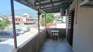 A balcony with a table and chairs, overlooking a street with parked cars and buildings. - JSW PRAMLee (George Town)