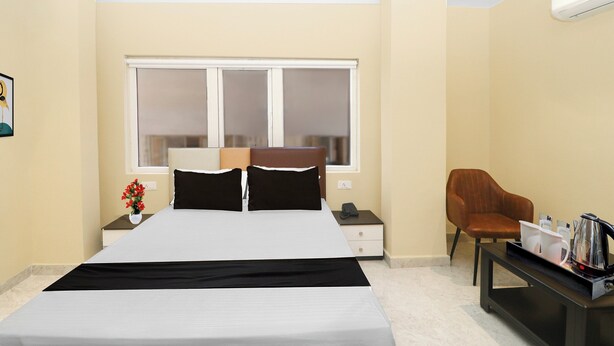 Una camera d'albergo con un letto, comodino, tavolo da notte, finestra, sedia e tavolino.