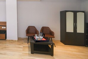 Ein Zimmer mit zwei braunen Ledersesseln, einem kleinen Tisch mit einer Ablage und einem dunkelbraunen Kleiderschrank.