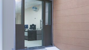 Un'area di accoglienza con una reception, un computer e un ventilatore a parete.