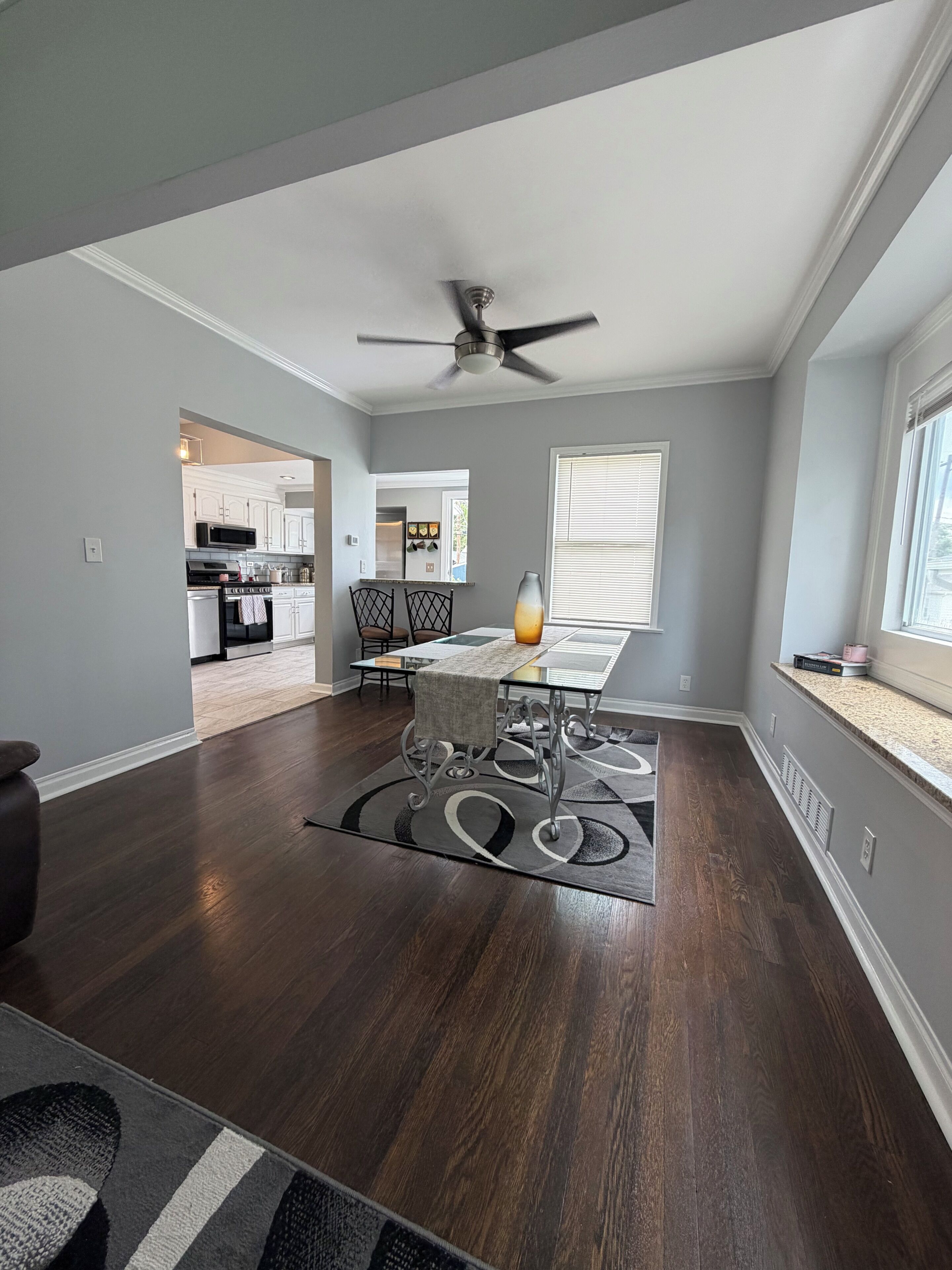 Un vaste espace de vie comprenant une table à manger, un ventilateur de plafond et une vue sur la cuisine.