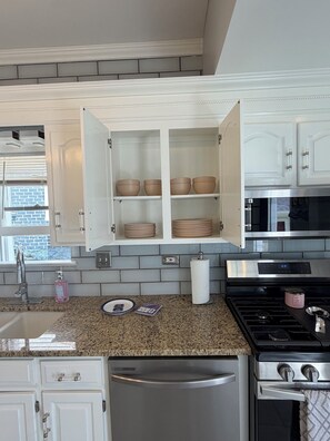 A kitchen with white cabinets, a stainless steel refrigerator, a microwave, and a gas stove.
