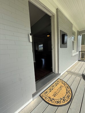 A house entrance with a doormat, a door, and a window.