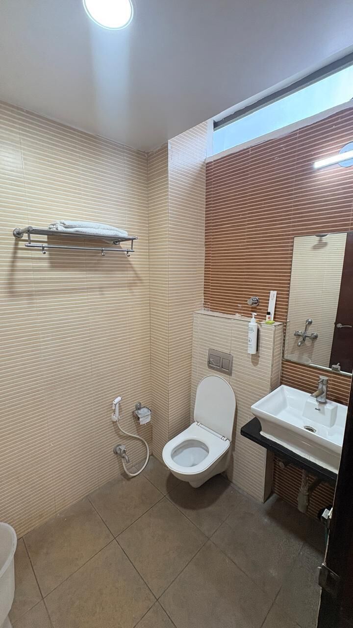 Un bagno con il water, un lavandino, uno specchio, un porta asciugamani e una zona doccia.