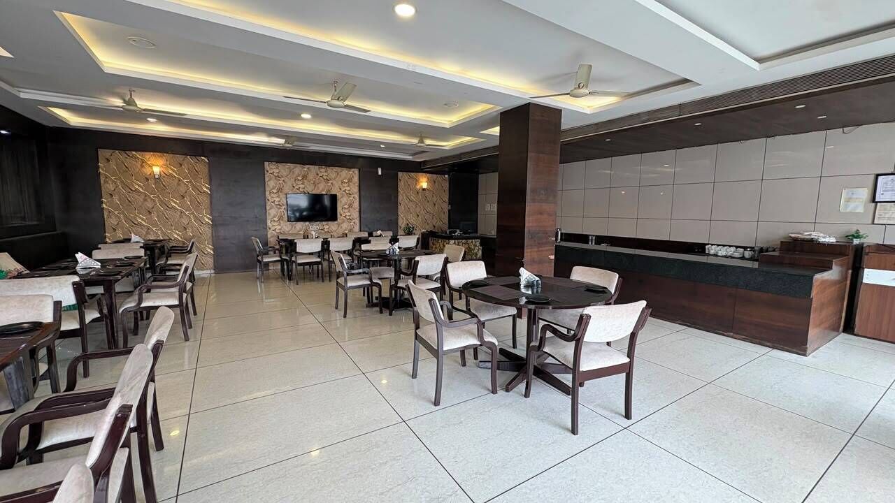 A hotel lobby with a reception desk, multiple seating areas, and a television screen.