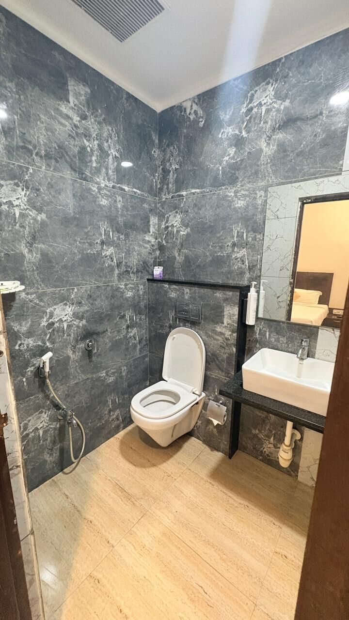 Un baño con inodoro, lavabo y paredes de mármol.