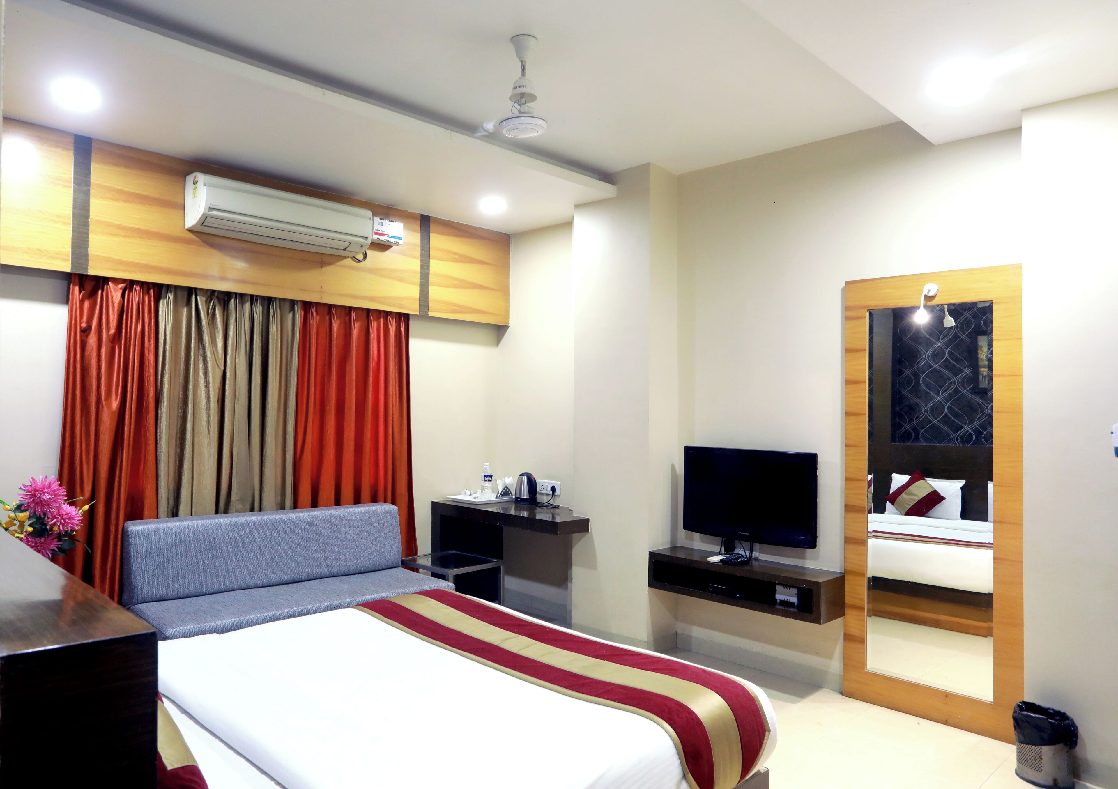 A hotel room with a bed, a television, a desk, and a mirror.