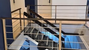 Un interior de varios niveles con escalera, barandales de metal y una pared azul decorativa.