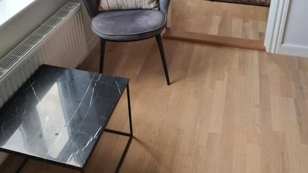 A compact room with a bed, a chair, a small table, and a view through a window. - Damm Hotell  (Frederikshavn)