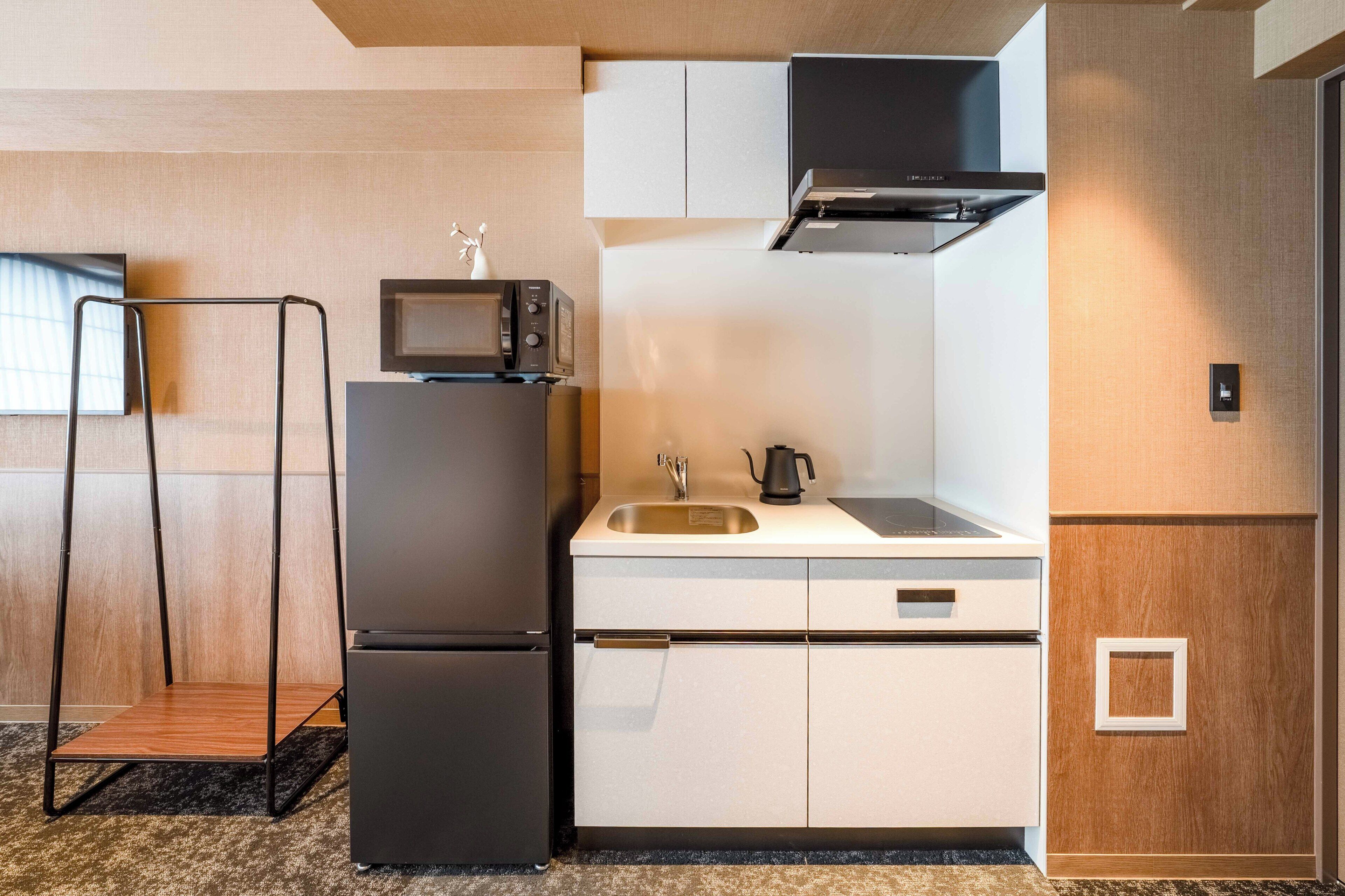 A compact kitchenette with a refrigerator, microwave, sink, and stove.