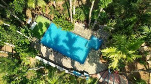 An aerial view of a swimming pool surrounded by lush greenery and palm trees. - Happy Feet Wayanad (Sulthan Bathery)