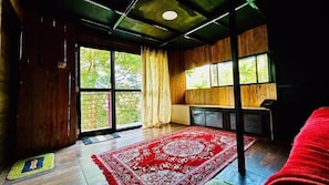 Una habitación con un ventanal grande, un tapete rojo estampado y un techo de madera.