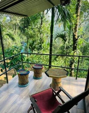 Un espacio al aire libre con mobiliario de mimbre y vista a follaje exuberante.
