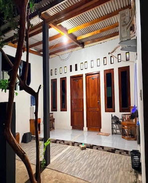 A building with a covered porch, wooden doors, and a tiled floor.
