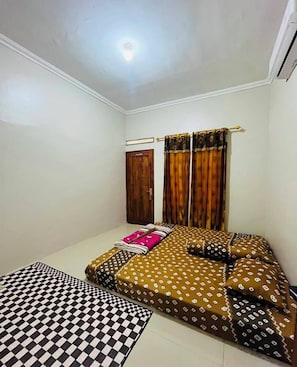 A bedroom with a bed, a window with curtains, a door, and a ceiling light.