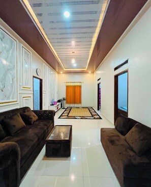 A living room with a sofa set, a coffee table, a patterned rug, and a ceiling with recessed lighting.