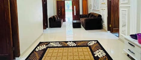 A hallway with a patterned carpet, a sofa, and a clock on the wall.