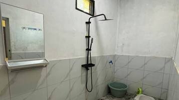 Et lille badeværelse med bruser, toilet og håndvask.