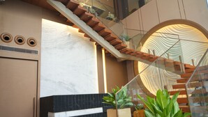 Un intérieur moderne avec un escalier, un mur doté d’ouvertures circulaires et des plantes en pot.