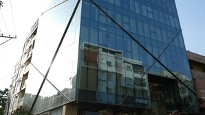 Un bâtiment moderne en verre, doté d’une entrée imposante et d’une enseigne indiquant « DAAWAT BIRYANI HOUSE ».