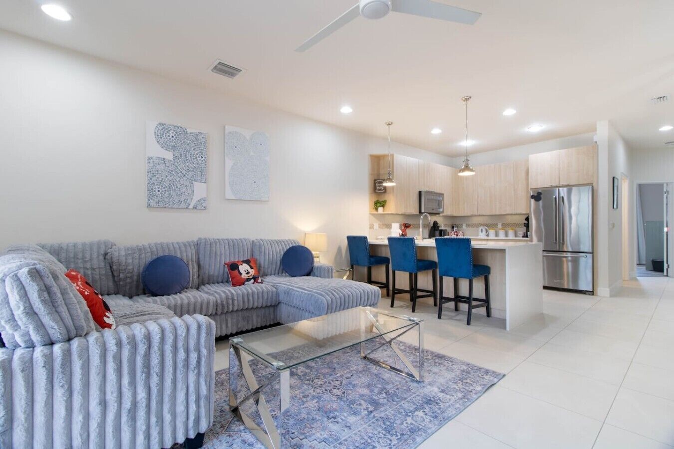 A modern living room with a sofa, a glass coffee table, and a blue rug.