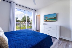 A bedroom with a large bed, a white dresser, and a painting of a beach scene. - Mickeys Hideaway |Mins to Disney, Private Pool (Clermont)