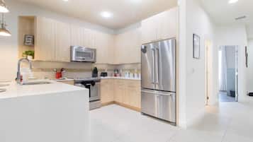 A modern kitchen with stainless steel appliances, a central island, and light wood cabinetry.