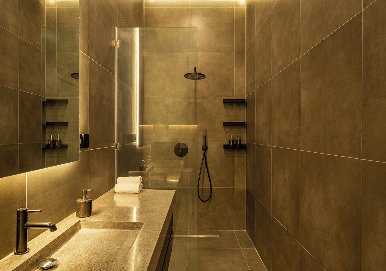 A modern bathroom with a large mirror, a shower, and a vanity with a sink and towel rack.