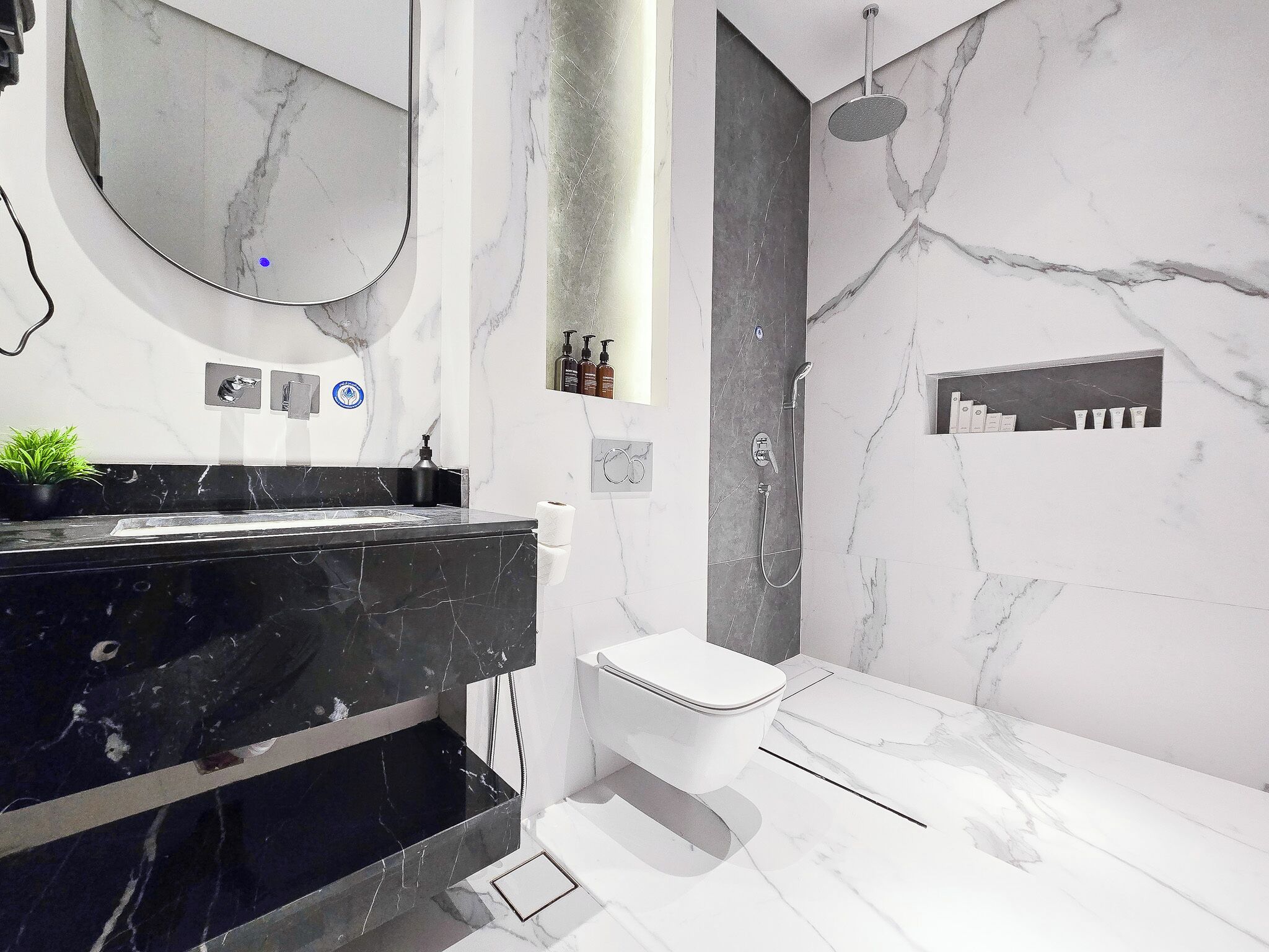 A modern bathroom with a black marble vanity, a white toilet, and a shower area.