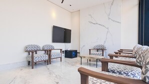 A modern living room with a flat-screen TV mounted on the wall, a marble floor, and patterned furniture. - MR STAY (Riyadh)