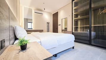 A modern bedroom with a bed, bedside table, and a large mirror.
