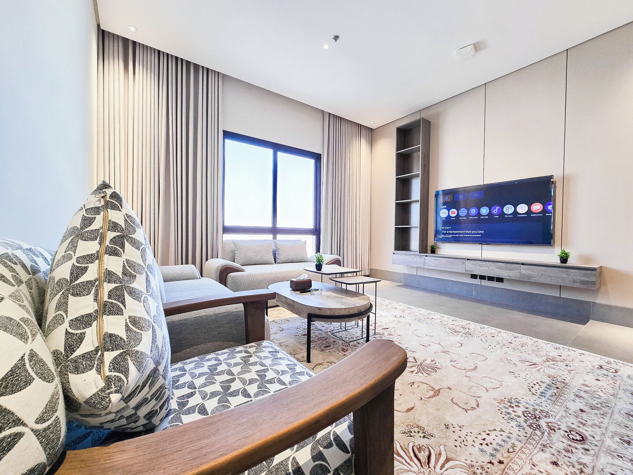 A modern living room with a sofa, coffee table, and a flat-screen TV mounted on the wall.