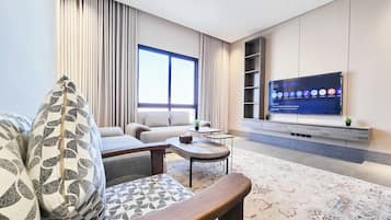 A modern living room with a sofa, coffee table, and a flat-screen TV mounted on the wall.