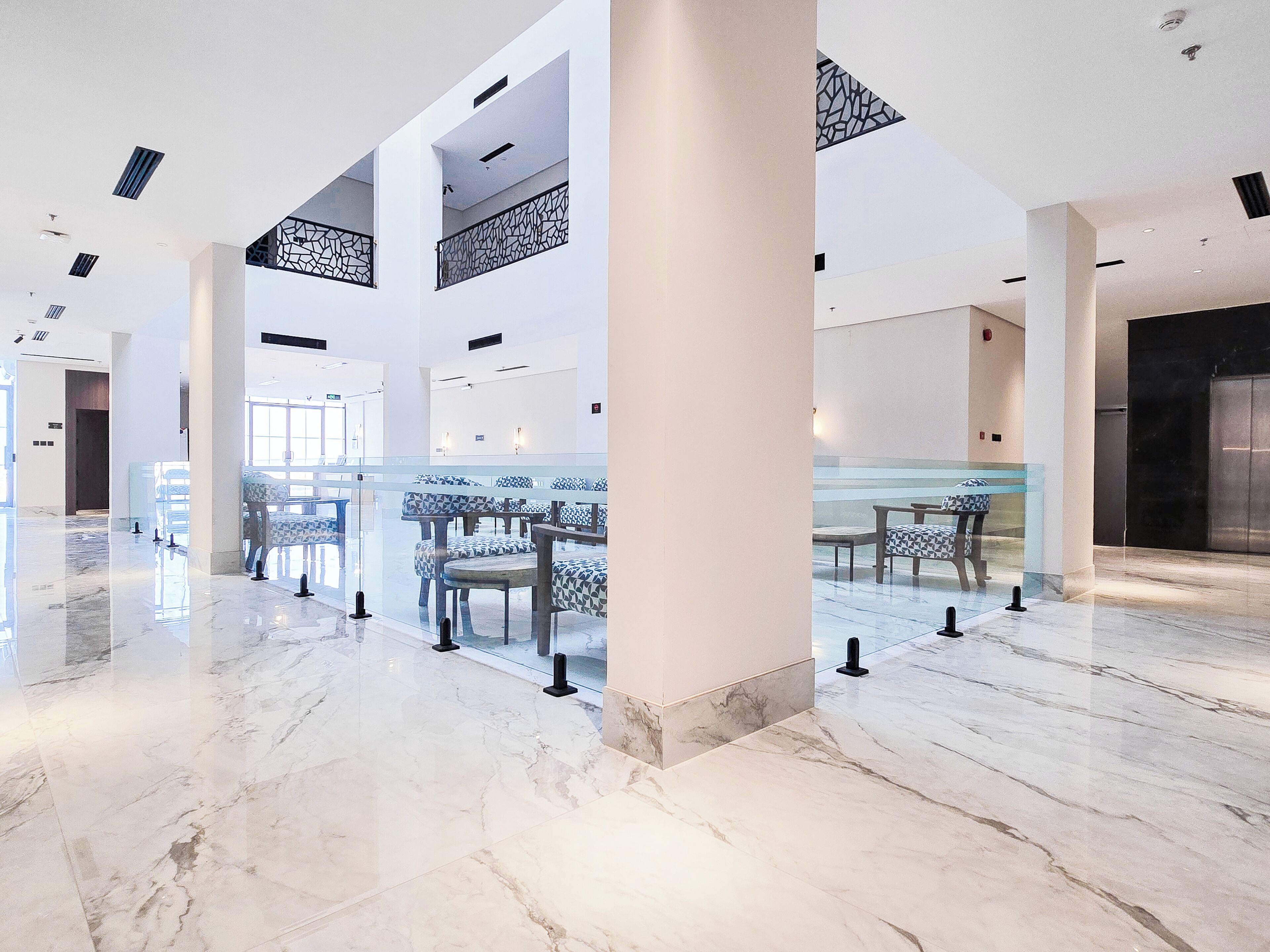 A spacious lobby with marble flooring, seating areas, and a modern design.