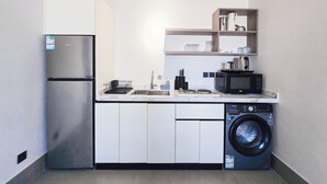 A compact kitchen with a refrigerator, microwave, sink, and washing machine. - MR STAY (Riyadh)