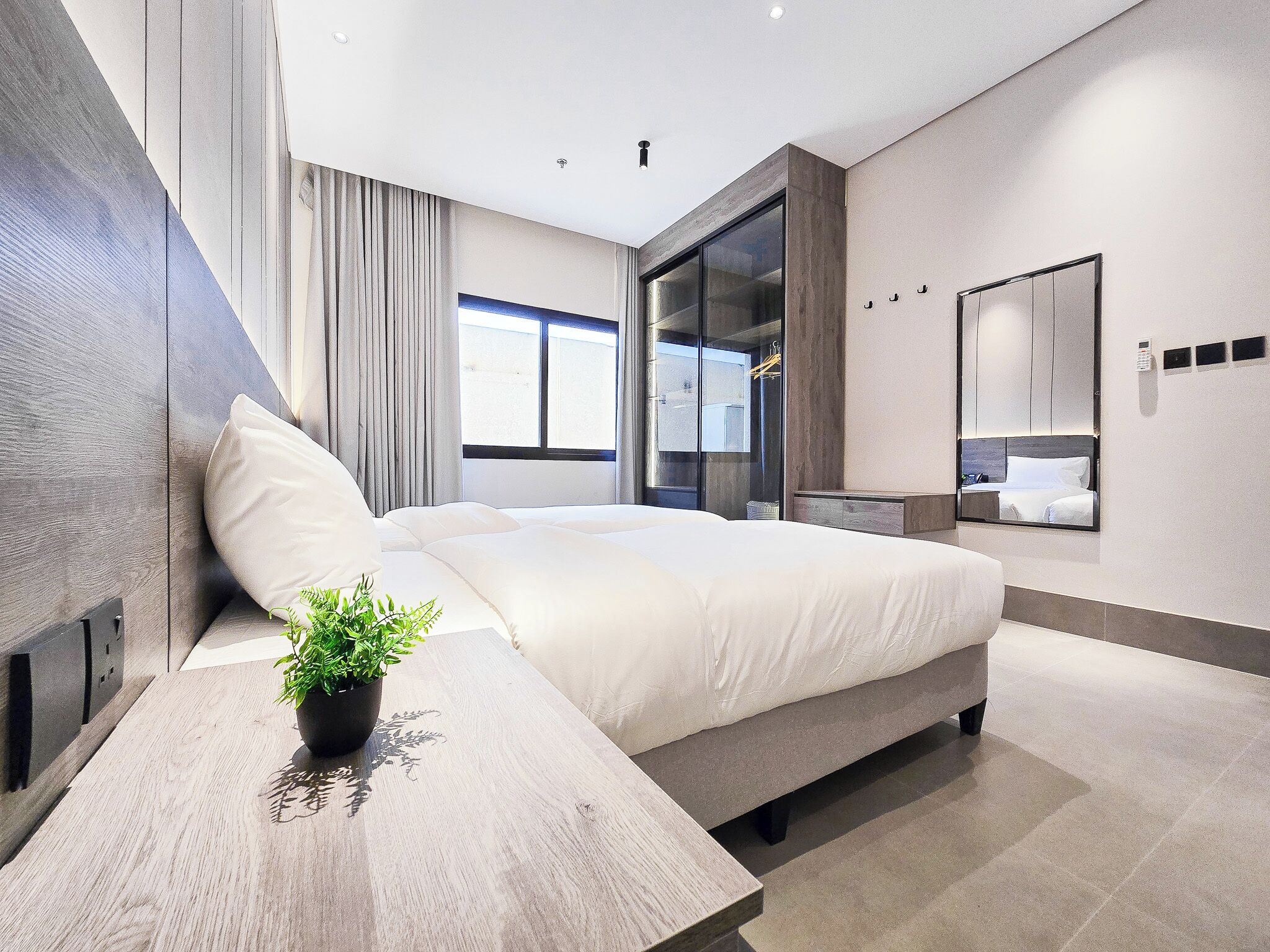 A modern bedroom with a bed, bedside table, and a potted plant.