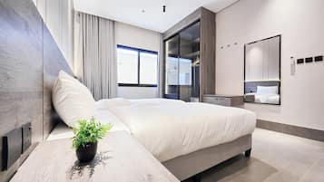 A modern bedroom with a bed, bedside table, and a potted plant.