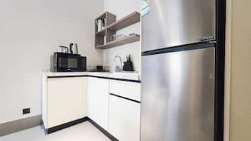 Una cocina moderna con armarios blancos, un refrigerador de acero inoxidable, un microondas y un lavamanos.