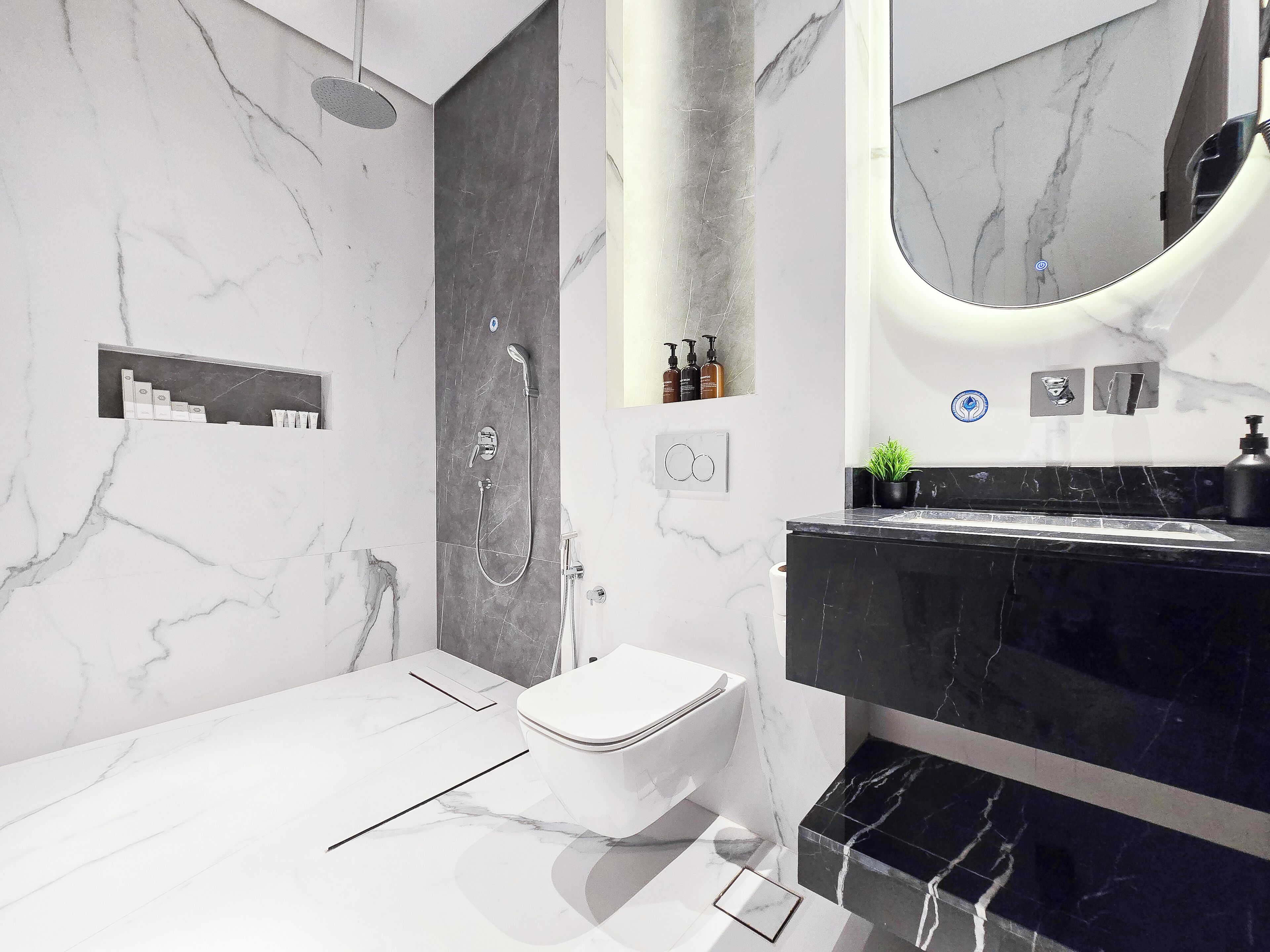 A modern bathroom with a marble floor, a black sink, a white toilet, and a shower area.