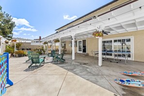 Ein Patio mit grünen Stühlen, einem Tisch und einer überdachten Sitzgelegenheit.