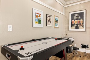 Ein Billardtisch mit einem Logo, ein Schlagzeug und gerahmte Kunstwerke an der Wand.