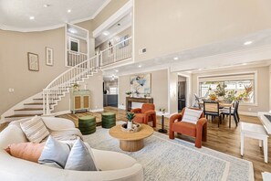 A spacious living area with a staircase, a dining area, and a piano. - 1 Step to the Park - 6BR • Game On! Arcade • BBQ • Pool Table - Long Stay Luxury (Huntington Beach)