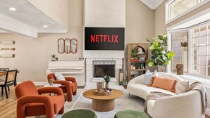 Uma sala de estar com lareira, televisão e estante de livros.