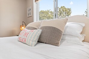 A bed with multiple pillows and a nightstand with a lamp. - 1 Step to the Park - 6BR • Game On! Arcade • BBQ • Pool Table - Long Stay Luxury (Huntington Beach)