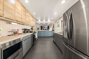 A modern kitchen with stainless steel appliances, wooden cabinets, and a central island. - 1 Step to the Park - 6BR • Game On! Arcade • BBQ • Pool Table - Long Stay Luxury (Huntington Beach)