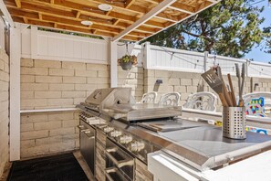 An outdoor kitchen with a grill, sink, and storage cabinets. - 1 Step to the Park - 6BR • Game On! Arcade • BBQ • Pool Table - Long Stay Luxury (Huntington Beach)