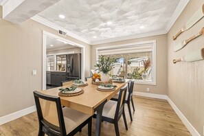 A dining area with a wooden table, chairs, and a decorative vase. - 1 Step to the Park - 6BR • Game On! Arcade • BBQ • Pool Table - Long Stay Luxury (Huntington Beach)