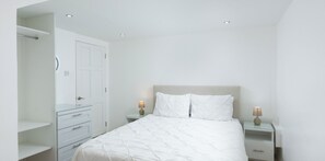 A bedroom with a bed, nightstands, a wardrobe, and a door. - Mango Court #3 - by ZenBreak (Porters)