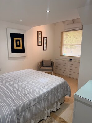 A bedroom with a bed, a chair, a dresser, and a window with blinds. - 3BR Holetown Near to Beach, Mango Court - by ZenBreak (Porters)