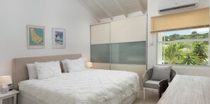 Een slaapkamer met een bed, een stoel, een bureau, een kaart en een raam met uitzicht.